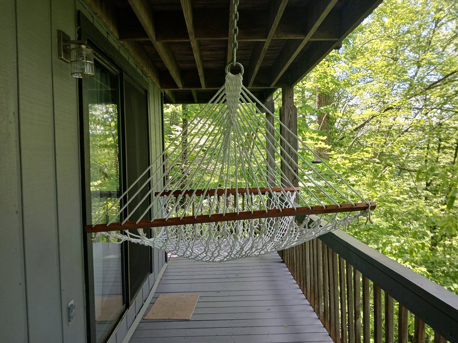 A hammock on the wraparound deck, suspended in green